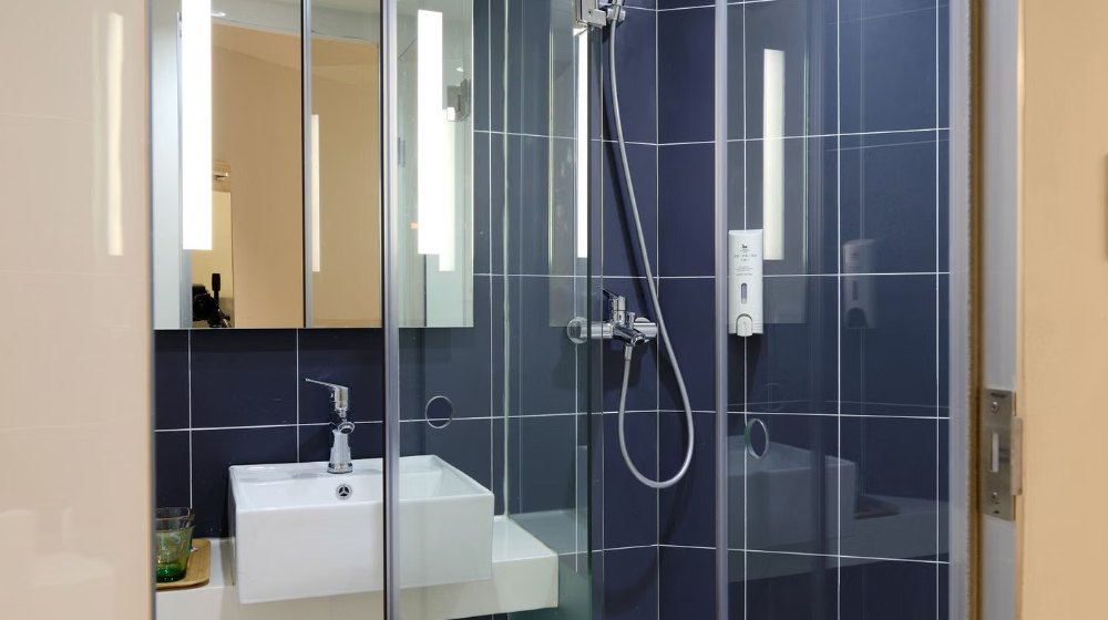 Vách tắm kính cố định 10 ly kẹp inox trong phòng tắm lát gạch xám